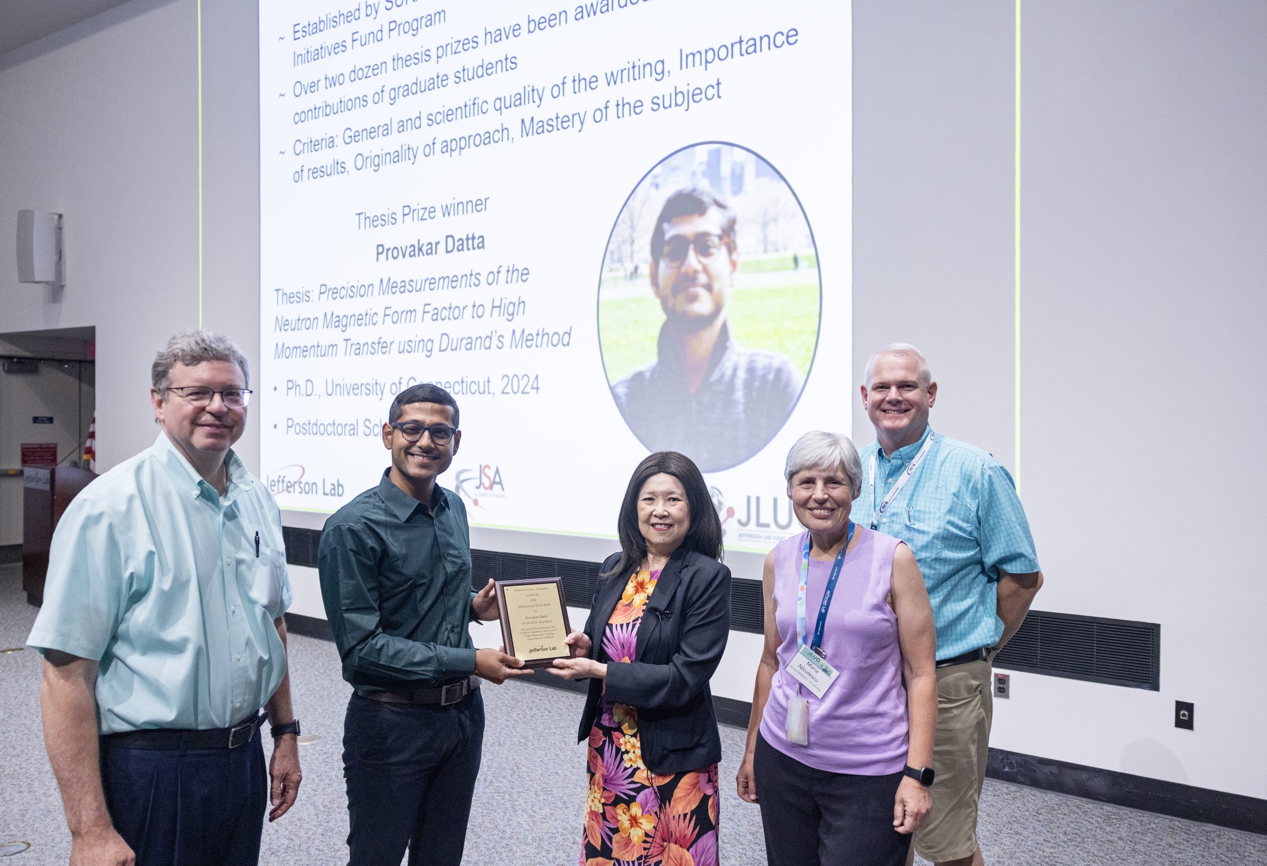 From left: David Dean, Provakar Datta, Elizabeth Lawson, Loana “Maria” Niculescu, and Matthew Shepherd pose for a group photo after Datta wins the thesis award during the Jefferson Lab User Organization (JLUO) annual meeting award ceremony held inside the CEBAF Center auditorium at Jefferson Lab in Newport News, Va., on June, 25, 2025. (Aileen Devlin | Jefferson Lab)